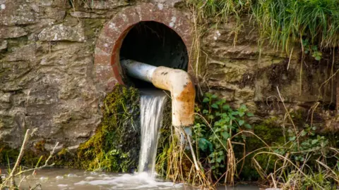 Getty Images Water flowing from a drain into a river