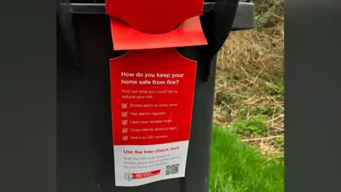 Avon Fire and Rescue Service Image of a bin hanger. It is red and lists ways in which residents can reduce the risk of home fires. The Avon Fire and Rescue logo is printed across the bottom of the hanger.