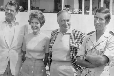 Getty Images Charles stands beside the UK ambassador, Reagan and his wife. The king wears a khaki uniform, while the others wear sweaters and suit jackets