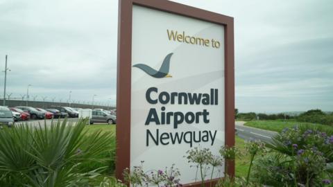 A signing saying "Welcome to Cornwall Airport Newquay" at the airport site's entrance