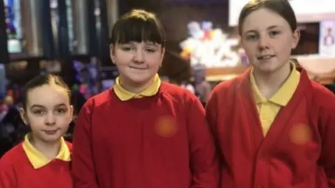 BBC (Left to right) Scarlet; Ava and Rebecca are in their red and yellow school uniforms