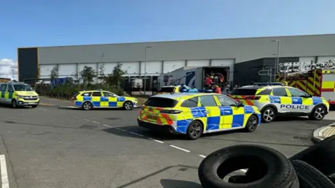 A number of emergency service vehicles parked outside a lorry