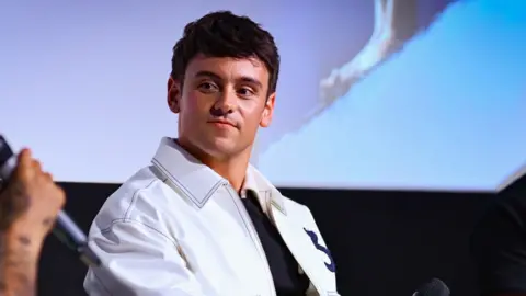 Tom Daley wearing a white jacket at a Q&A screening for the documentary, Tom Daley: 1.6 Seconds
