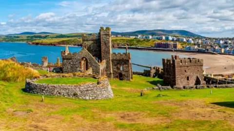 Picture of Peel Castle taken on a sunny day, overlooking Peel beach in the distance.