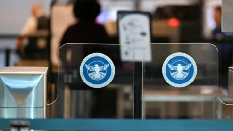 Reuters Clear glass gates with the seal of the Transportation Security Administration at an airport 