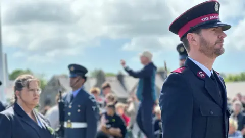 Captain Dylan Nieuwoudt of the Salvation Army in uniform with crowds behind him.