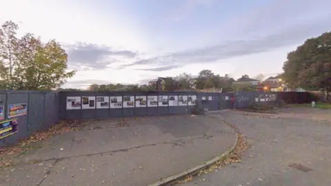 Google Grey boards block off the entrance road to a larger site.