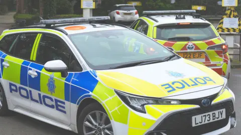 Two blue, white and yellow police patrol cars parked at the scene of a crime in Worthing.
