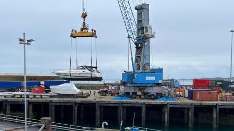 Boat being lifted into the QEII Marina via crane
