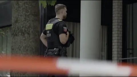 German police officer standing guard in front of police tape