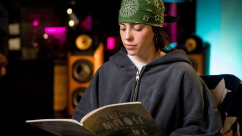 A picture of Billie Eilish reading The Moose Belongs to Me