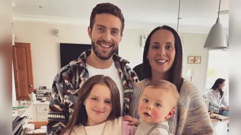 Sam, a woman in her mid-40s, with her partner and two children - a son and daughter.