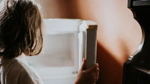 Getty Images A child looks into an empty fridge
