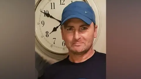 A man with a blue cap and black top