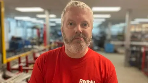A man with a beard in a red top