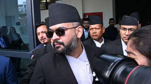 Balendra Shah walking through a door, swarmed by the media and surrounded by other men in suits