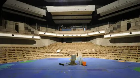 Haymarket Consortium A theatre auditorium with the seats removed and a mop, bucket and cable wheel left on the stage 