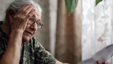 A generic image of a lady looking at a bill. 