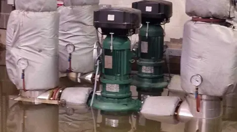 Local Democracy Reporting Service Electrical equipment partially submerged in flood water in a basement