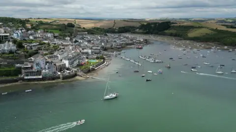 The town of Salcombe, from the air, showing the river, moored boats and a marina area.