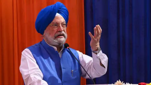 Getty Images India's federal Minister of Petroleum and Natural Gas Hardeep Singh Puri, wearing blue jacket and turban, with his hand raised, is addressing a gathering. 