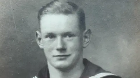 Bill Redston A young man with short hair in Navy uniform against a grey background