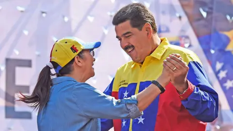 De Venezolaanse president Nicolas Maduro (R) danst met zijn vrouw Cilia Flores tijdens een demonstratie tegen het besluit van de Verenigde Staten om de sancties tegen verschillende hoge Venezolaanse functionarissen te hernieuwen, in Caracas op 12 maart 2016.