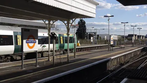 Norwood Junction from the platform with a train in the background, with tracks and TfL signage.