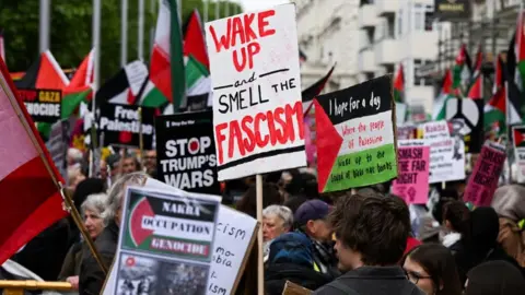 Reuters Crowds holding posters including one saying Wake Up and Smell the Fascism
