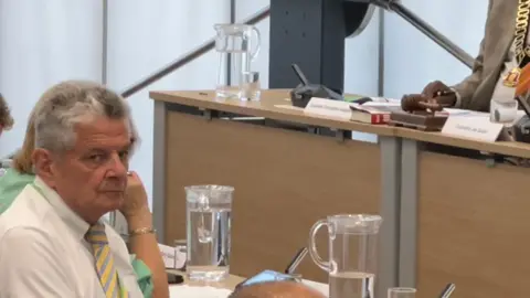 Nottinghamshire County Councillor Bert Bingham is pictured wearing a white shirt with yellow and grey-striped tie