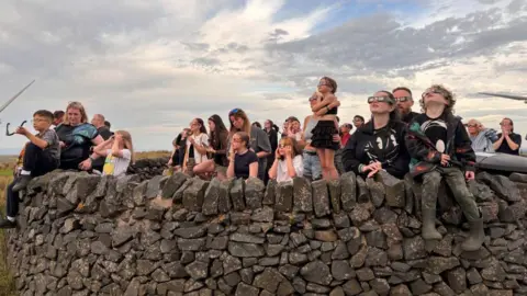 Clouds at Whitelee Wind Farm scuppered the view most of the time, but the crowd pictured here looked up when they parted to see a sliver of sun from behind the moon 