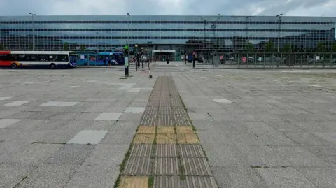 Geograph A station with a bus parked outside and people walking around the building 