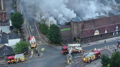 Eddie Mitchell Several fire engines surround a smouldering supermarket. 