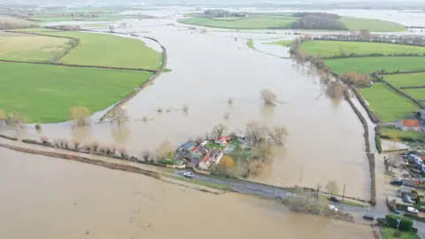 Paul Silvers A group of houses sit surrounded by floodwater. The picture has been taken by a drone and shows fields as far as the eye can see completely flooded. 