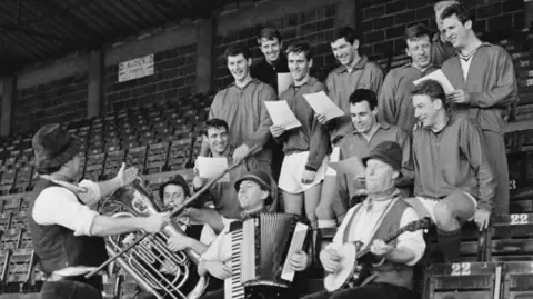 Getty Bristol City FC players rehearsing club song with singer Adge Cutler 