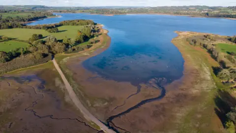 An image showing Chew Valley Lake which has dried out from the hot weather.