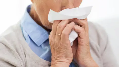 Getty Images A generic image of a woman blowing into a tissue
