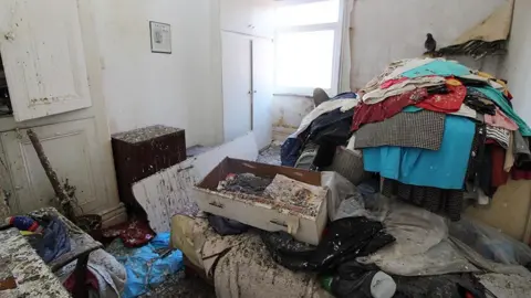 Blackpool Council The bedroom, also covered in droppings with high piles of clothes and a drawer full of rubbish to the right, a white cupboard to the left 