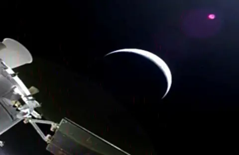 NASA A slightly grainy image from Orion showing a planet - perhaps the moon, as a sliver with most of it in darkness, and part of Orion in the corner.