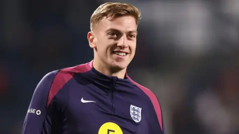 Liam Delap smiling in an England training top