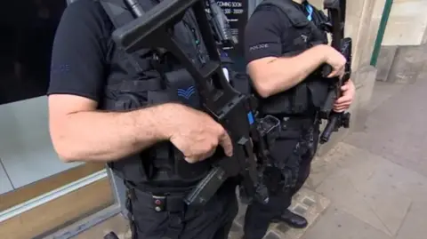 Two armed police officers hold their guns 