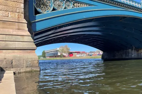 A view under an arch of Trent Bridge, with Nottingham Forest's City Ground in the background
