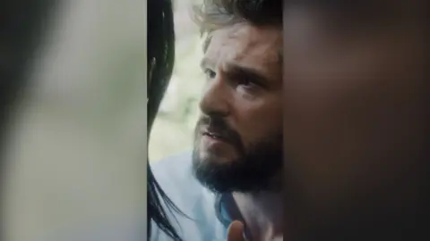 A bearded man looks desperately into a woman's eyes.