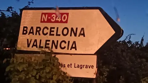 An image of a road sign in a hedge directing drivers to Barcelona and Valencia along the N-340 route. 