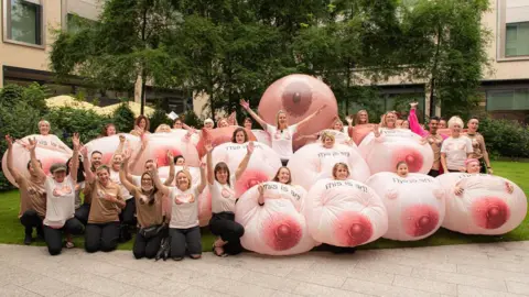 Vicky Martin A group of people wearing an inflateable breast costume stood outside of Meta HQ in London