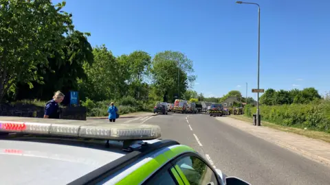 A police car and Cadent vehicles in the road