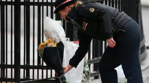AFP A police officer prepares to lay flowers near London bridge