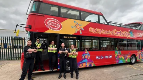 Cambridgeshire Constabulary  Police officers standing in front of a bus with their arms crossed