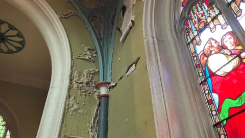 Leanne Harper/BBC The interior of a church with light green paint peeling off the walls. 