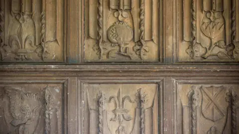 Wood carvings into oak panels include a pomegranate for Catherine of Aragon 